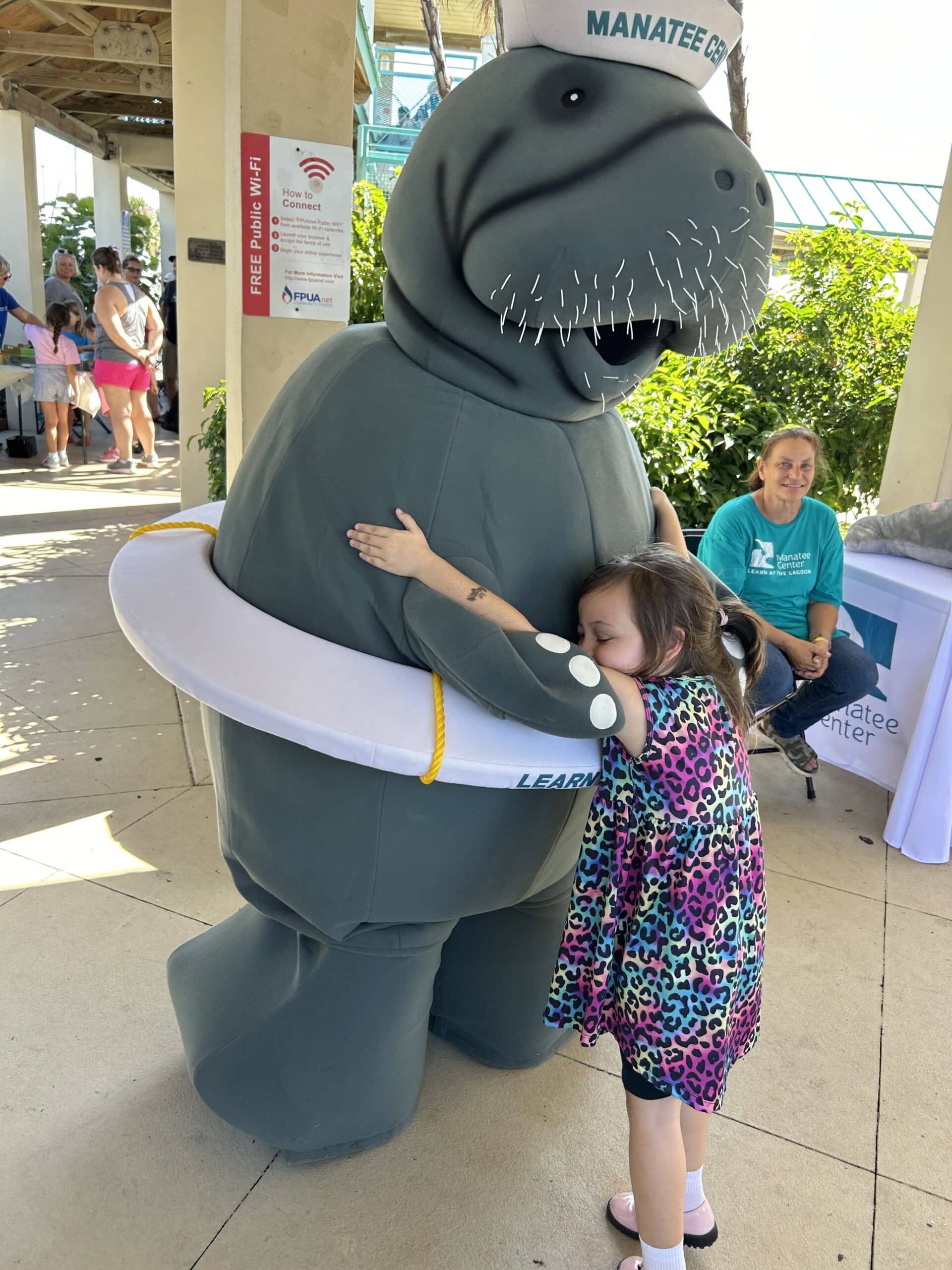 young girl hugging manatee costume