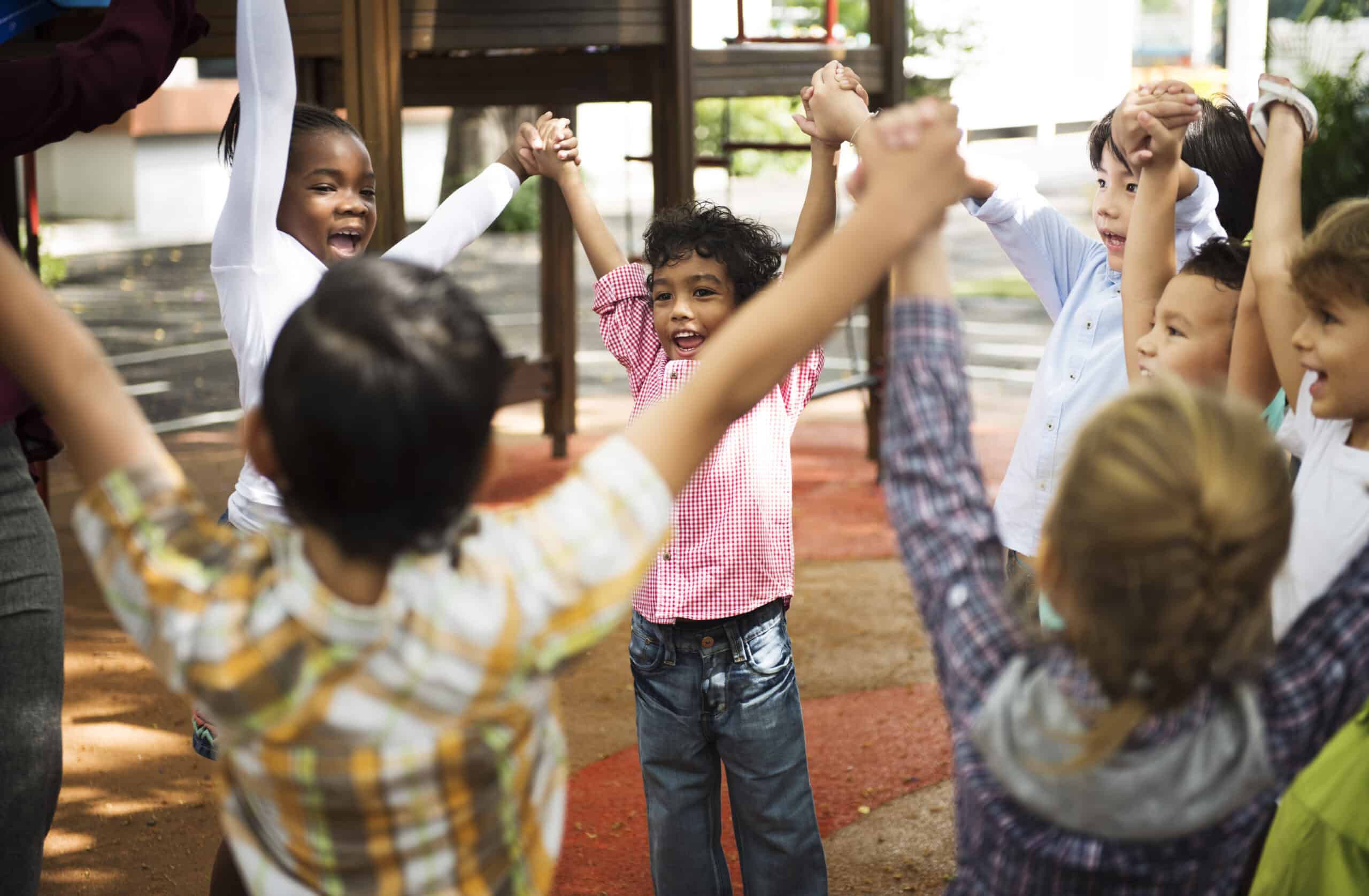 Group of diverse kindergarten students standing holding hands to